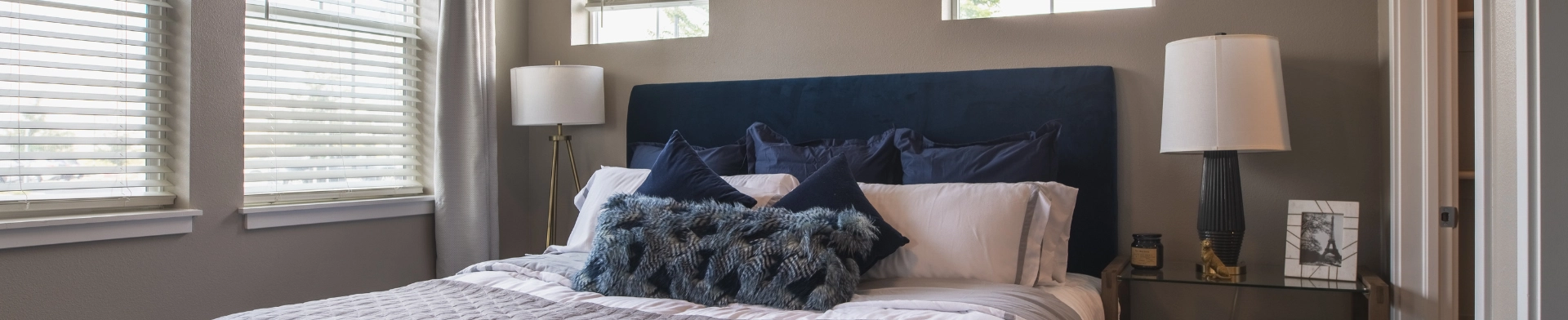 Modern bedroom with blue pillows and lamp.