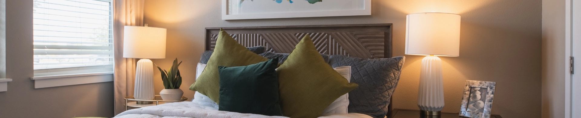 Cozy bedroom with pillows and lamps.