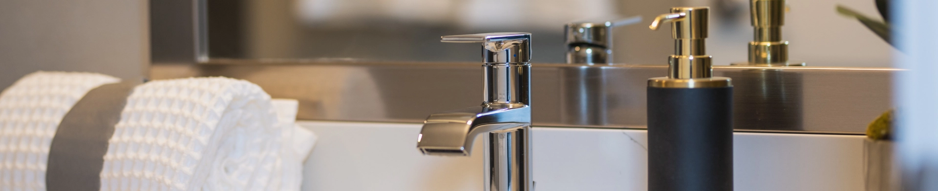 Modern bathroom sink with towel and soap dispenser.